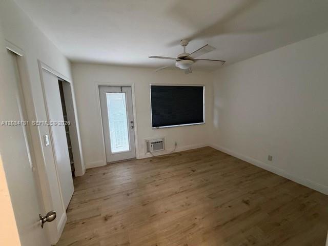 An empty bedroom features light wood-look flooring, a ceiling fan, and a glass-paneled door — 500 Layne Blvd # 19, Hallandale Beach FL 33009, HALLANDALE BEACH, FL