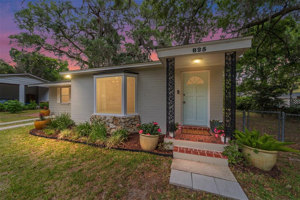 A light-colored brick house features a bay window, a light blue front door, and landscaping — 825 SE 13TH STREET, OCALA, FL