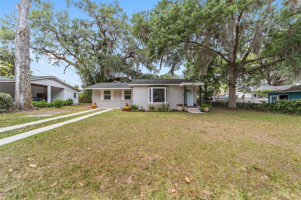 A single-story house with a light gray exterior, a bay window, and a concrete driveway — 825 SE 13TH STREET, OCALA, FL