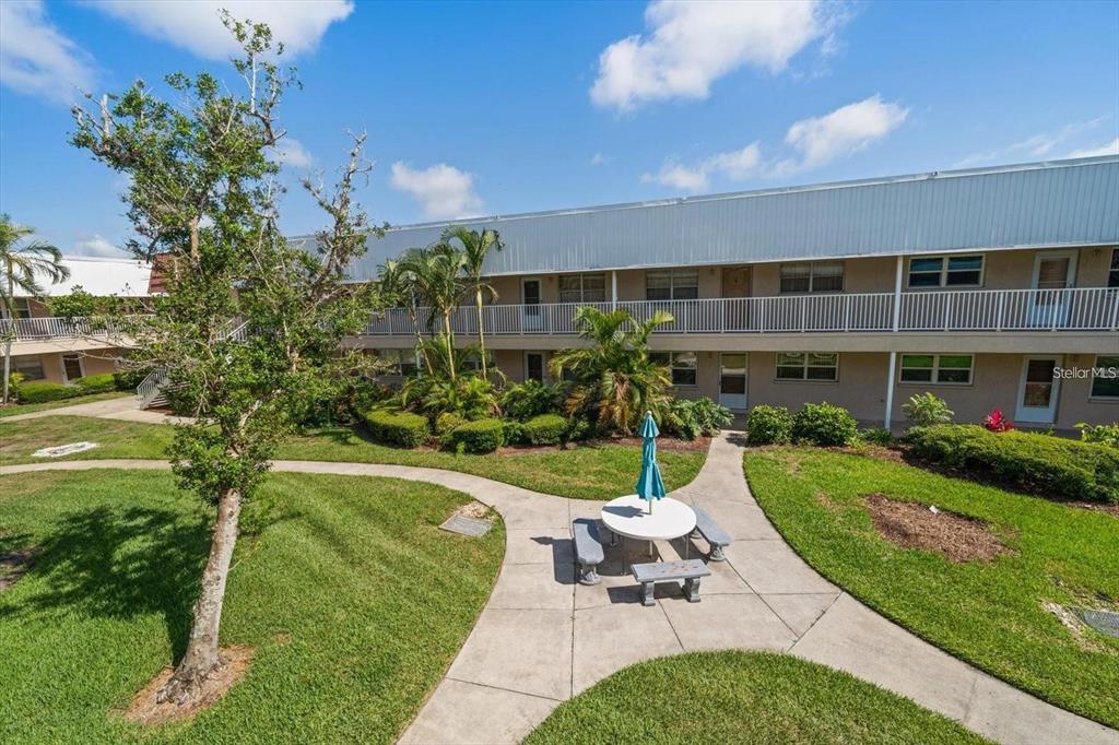 An outdoor courtyard features a concrete patio with a table, benches, and a building exterior — 10038 62ND TERRACE N UNIT 17, ST PETERSBURG, FL