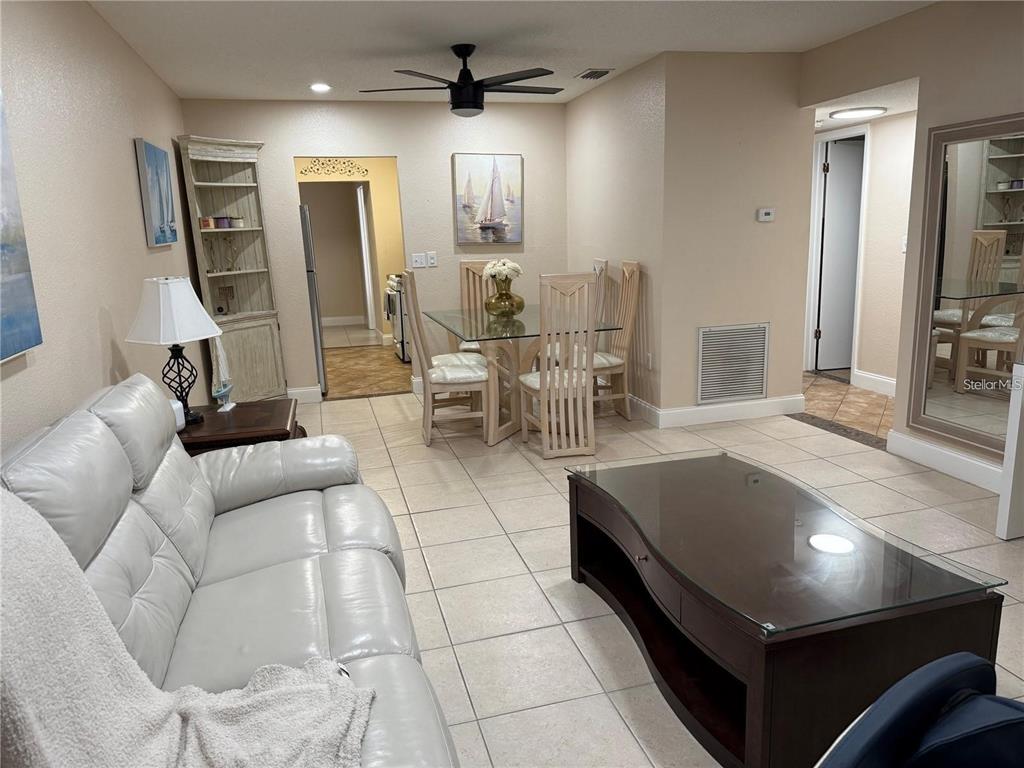 A living and dining area with tile floors, a glass-top table, and a white sofa — 10038 62ND TERRACE N UNIT 17, ST PETERSBURG, FL