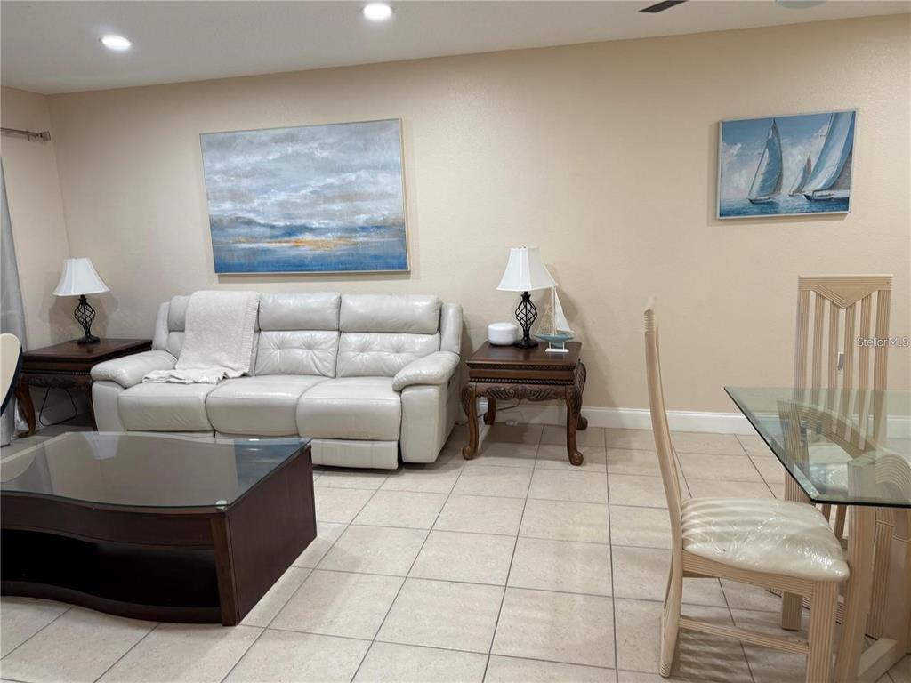 A living room features a white leather sofa, glass coffee table, and two wall paintings — 10038 62ND TERRACE N UNIT 17, ST PETERSBURG, FL