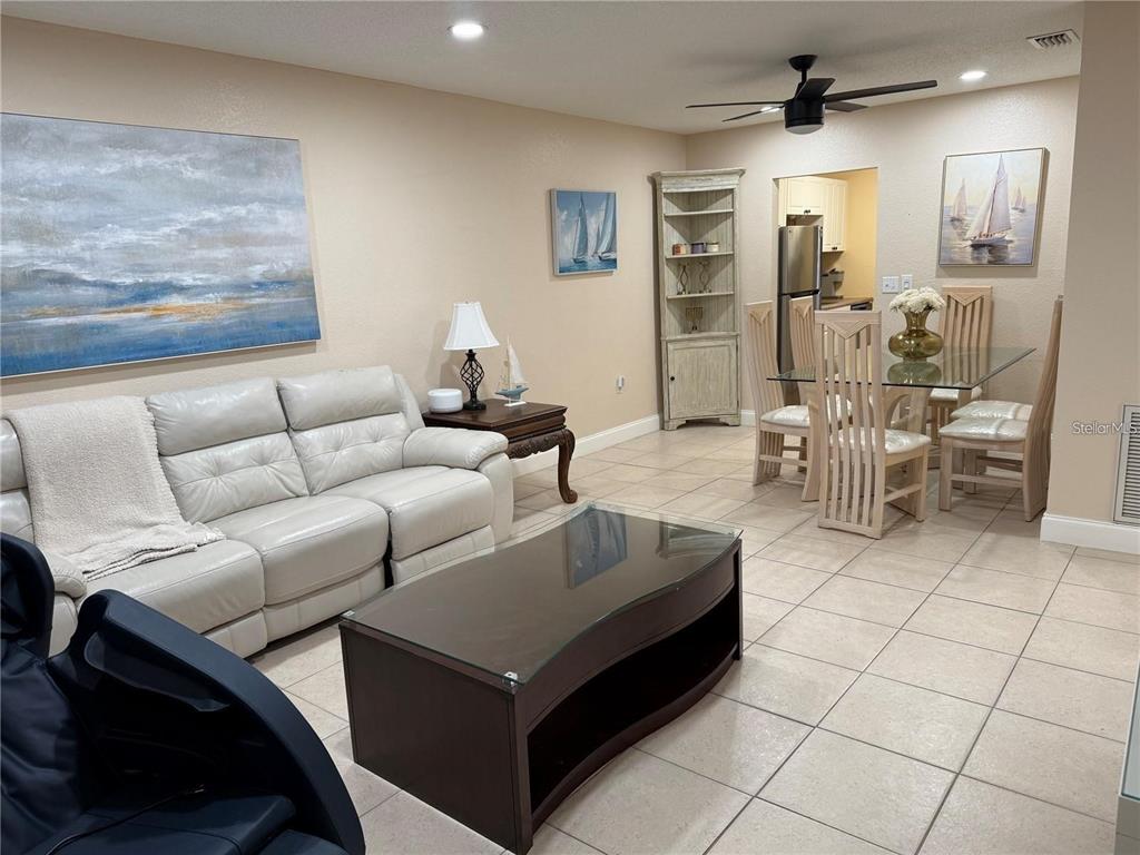A living room and dining area feature tile flooring, a white sofa, and glass-topped tables — 10038 62ND TERRACE N UNIT 17, ST PETERSBURG, FL