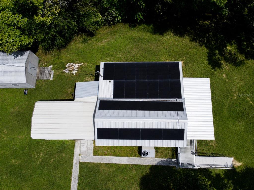 An aerial view of a house roof featuring multiple solar panel arrays and metal roofing — 5811 11TH STREET, ZEPHYRHILLS, FL