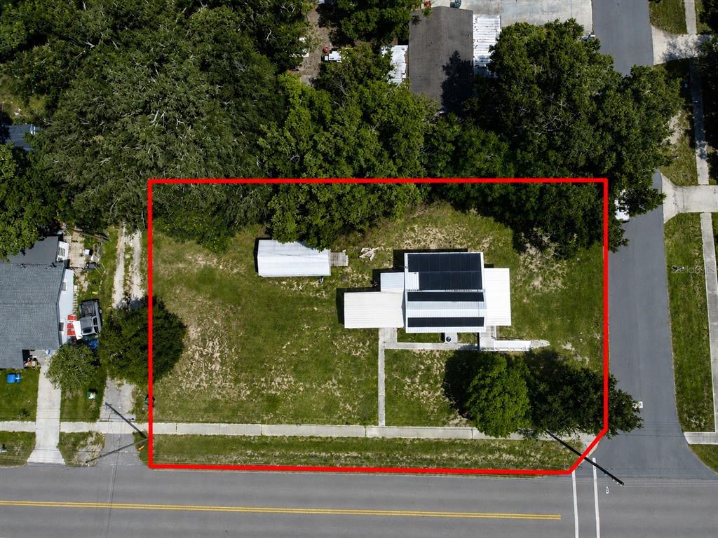 An aerial view shows a house with solar panels on a large, tree-lined residential lot — 5811 11TH STREET, ZEPHYRHILLS, FL