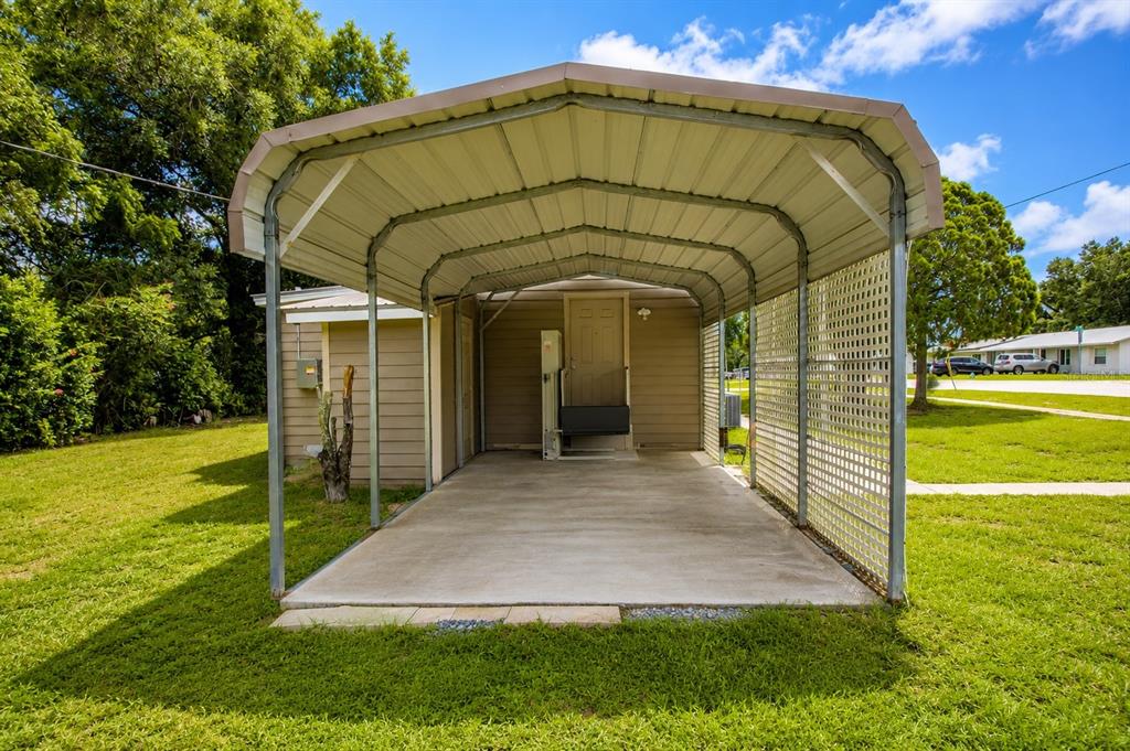 A metal carport with a concrete floor sits attached to the side of a house — 5811 11TH STREET, ZEPHYRHILLS, FL