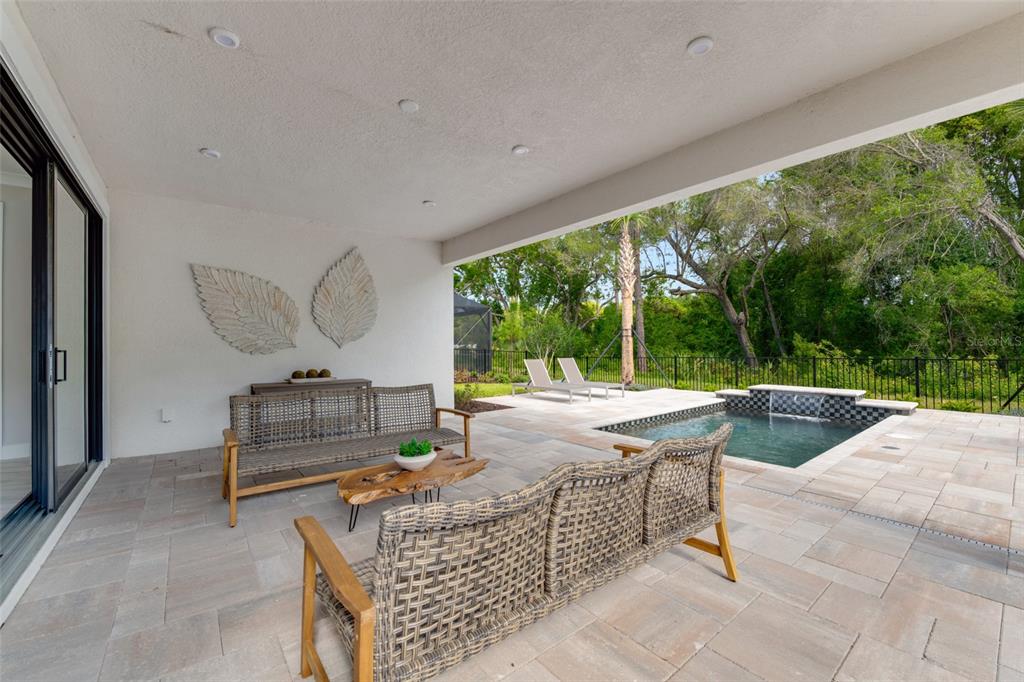 A covered patio features outdoor furniture, a small pool with a waterfall, and a wooded view — 1193 CRESSWIND BOULEVARD, DELAND, FL