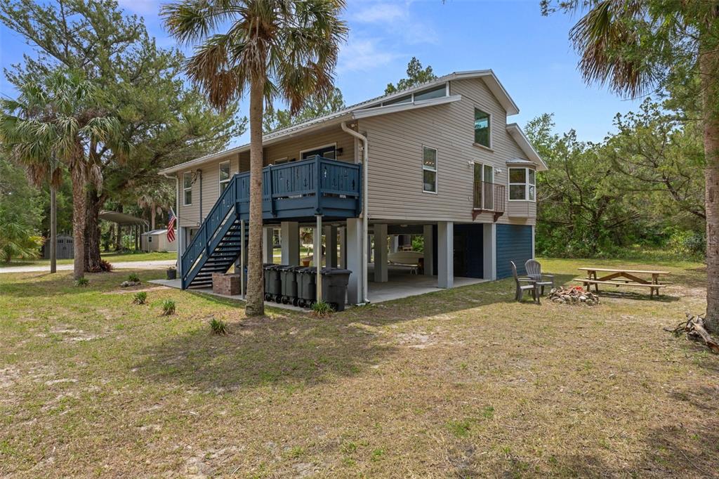 An elevated house with tan siding, a blue deck, and a picnic area underneath — 2272 S TODD POINT, HOMOSASSA, FL