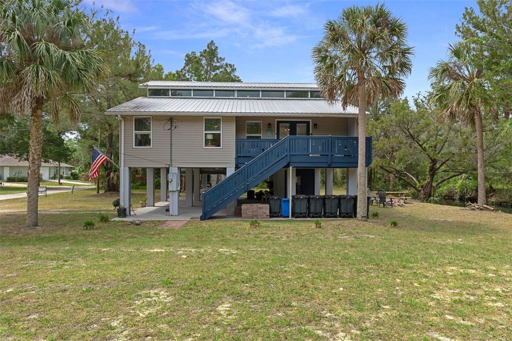 A two-story elevated house with a metal roof, blue deck, and stairs on a lawn — 2272 S TODD POINT, HOMOSASSA, FL