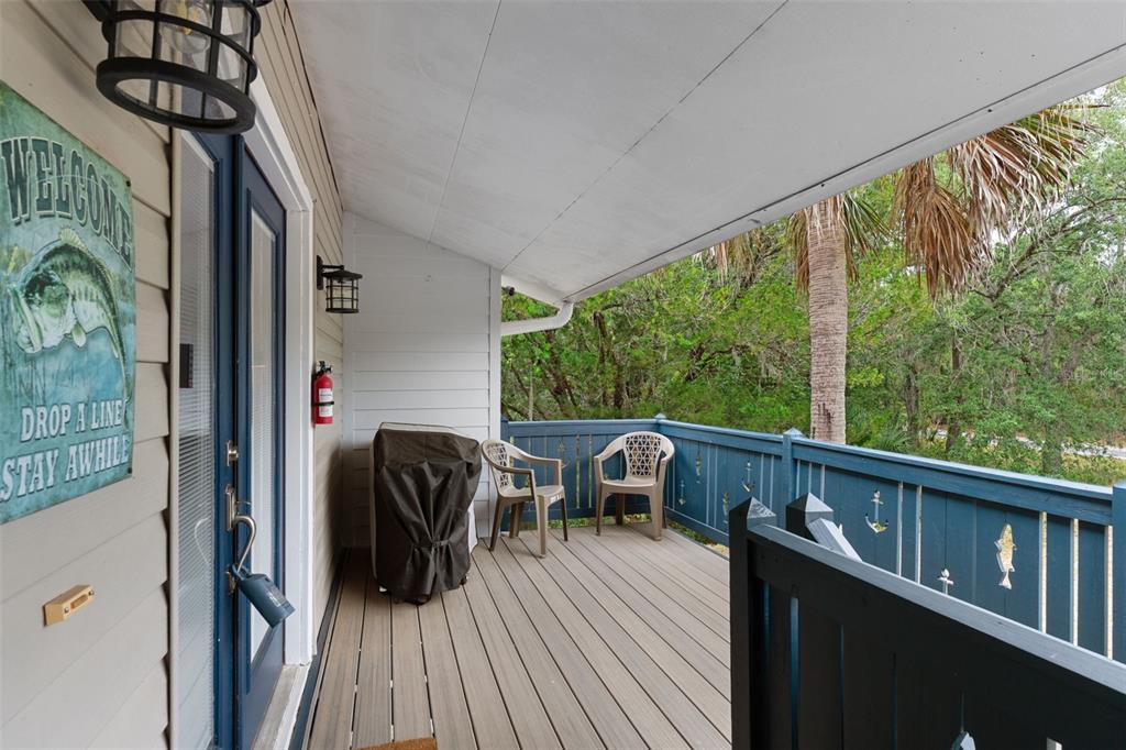 A covered wooden deck features two chairs, a grill, and a blue railing with cutouts — 2272 S TODD POINT, HOMOSASSA, FL