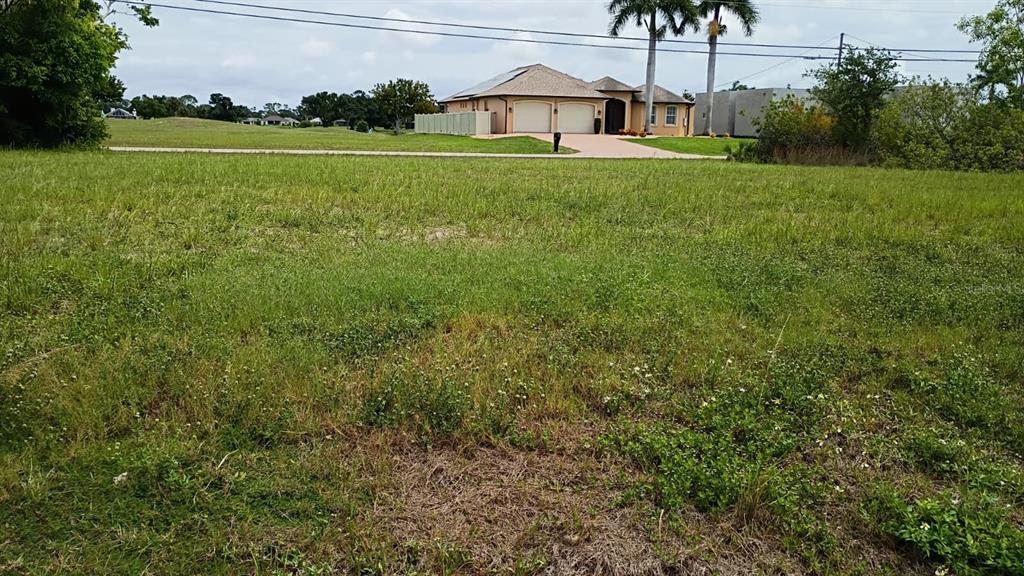 A vacant grassy lot sits in front of a suburban house with a two-car garage — 2918 NW 14TH TERRACE, CAPE CORAL, FL