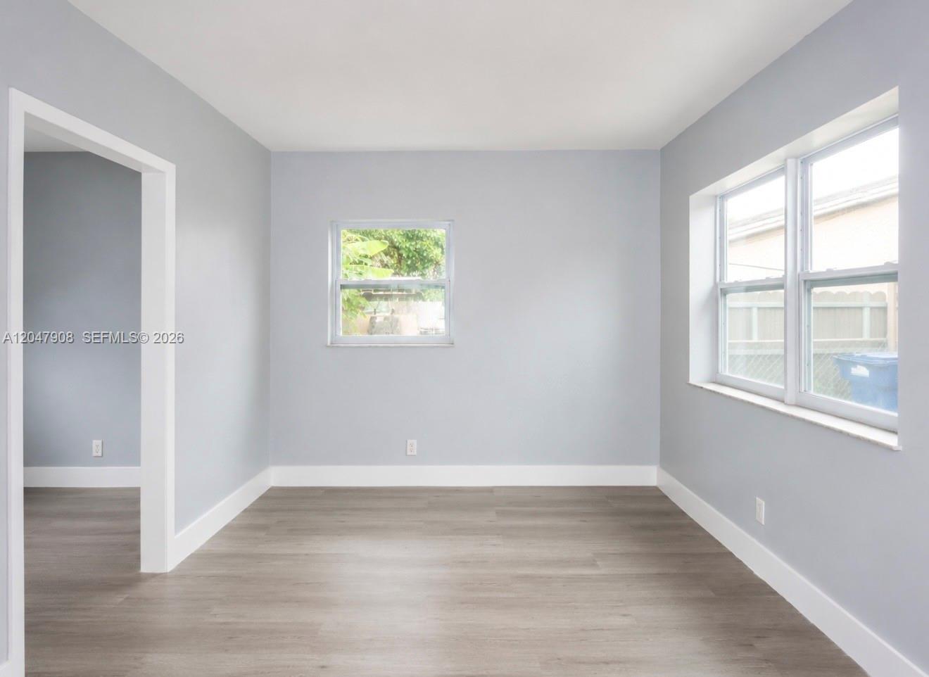 An empty room features light gray walls, white trim, and wood-look flooring — 432 NW 103rd St # 2, Miami FL 33150, MIAMI, FL