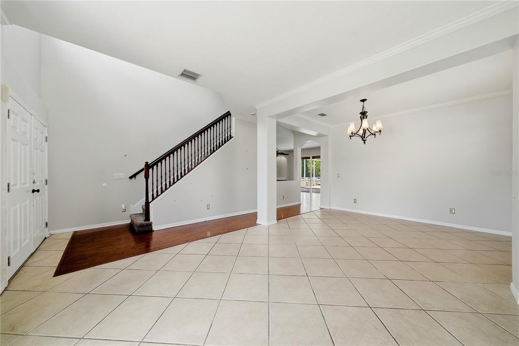 A foyer with tile flooring, a wooden staircase, and an adjacent dining area with a chandelier — 11335 VILLAGE BROOK DRIVE, RIVERVIEW, FL