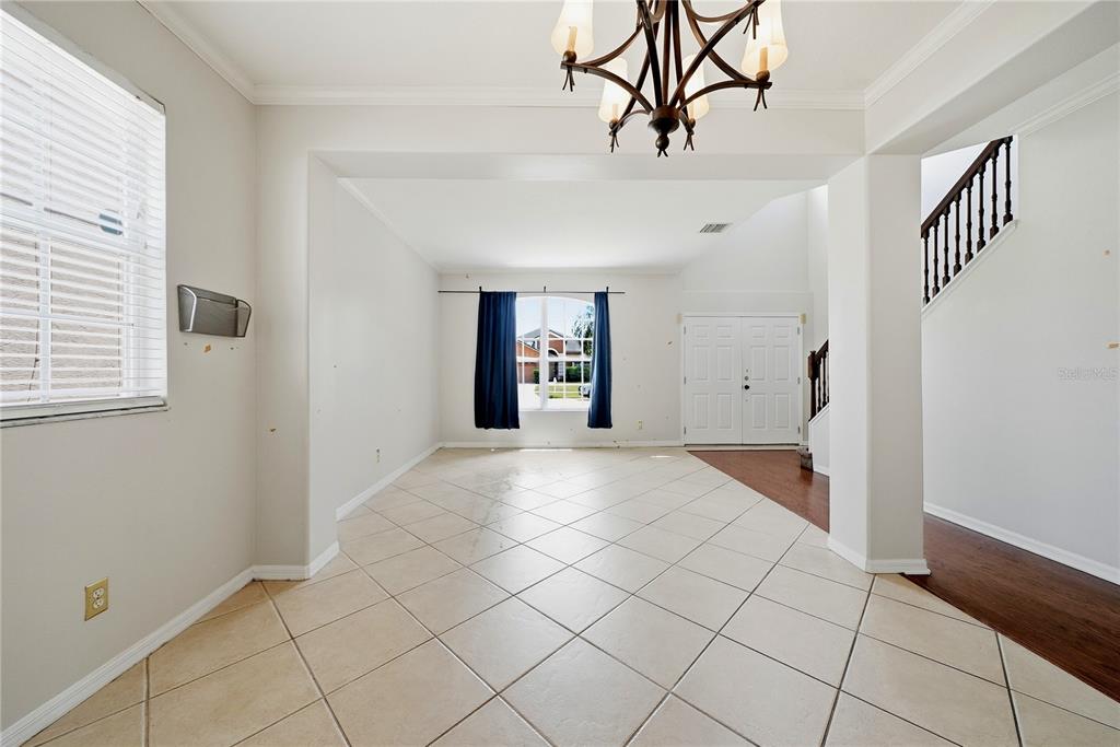 An empty dining room features tile flooring, a chandelier, and a view of the front entrance — 11335 VILLAGE BROOK DRIVE, RIVERVIEW, FL