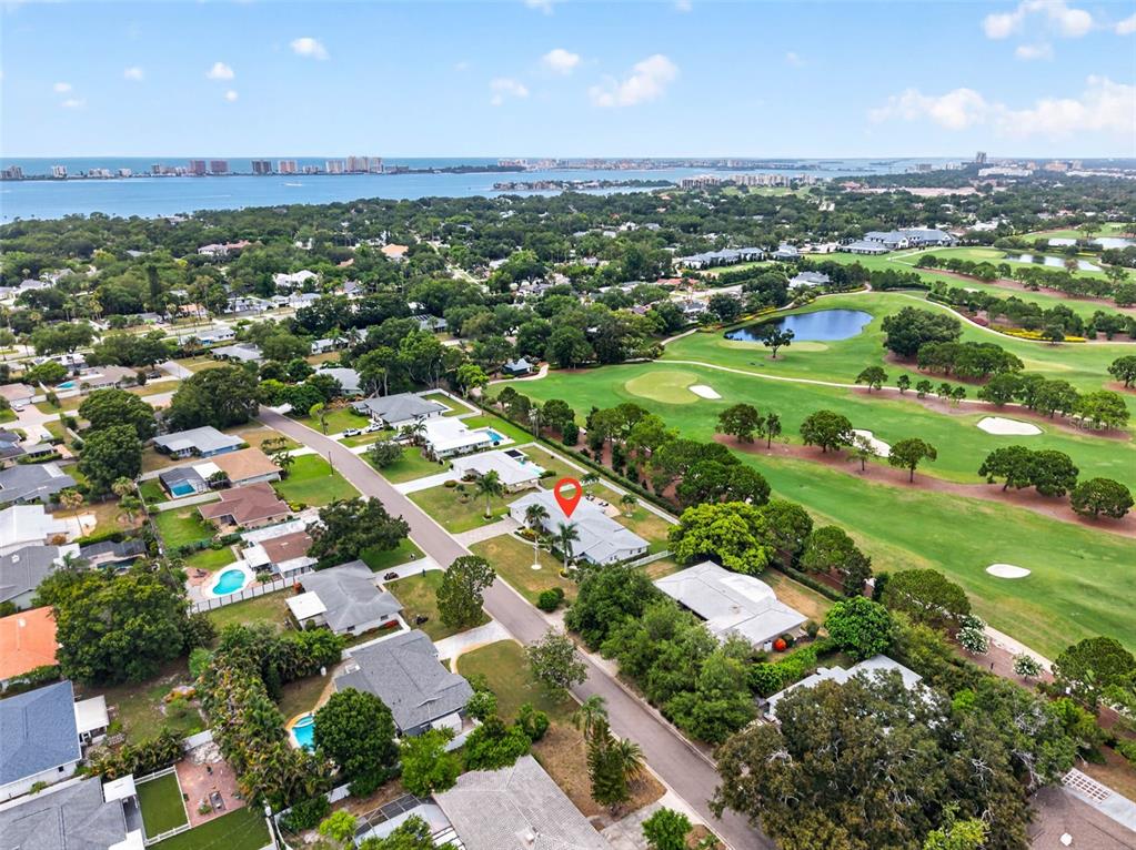 An aerial view shows a residential neighborhood bordering a golf course and the ocean — 616 PINELAND AVENUE, BELLEAIR, FL