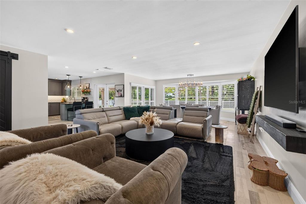 A living room features a large sectional sofa, a circular coffee table, and a wall-mounted television — 616 PINELAND AVENUE, BELLEAIR, FL