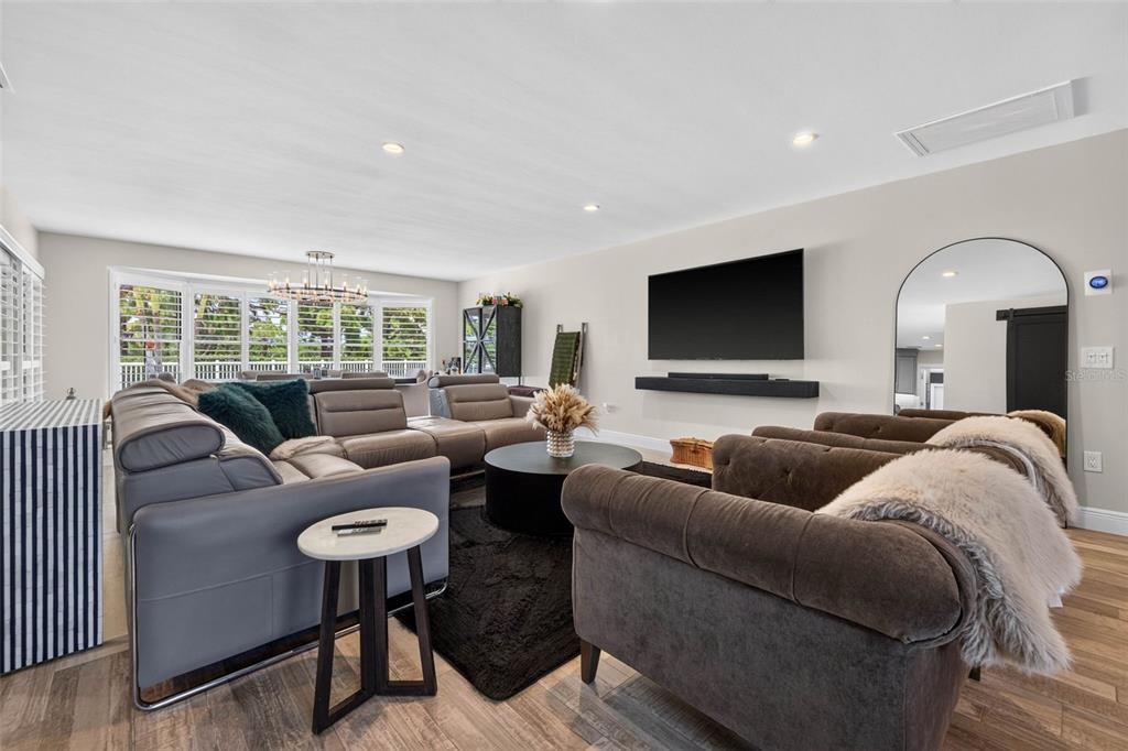 A living room features a large gray sectional, two brown armchairs, and a wall-mounted television — 616 PINELAND AVENUE, BELLEAIR, FL
