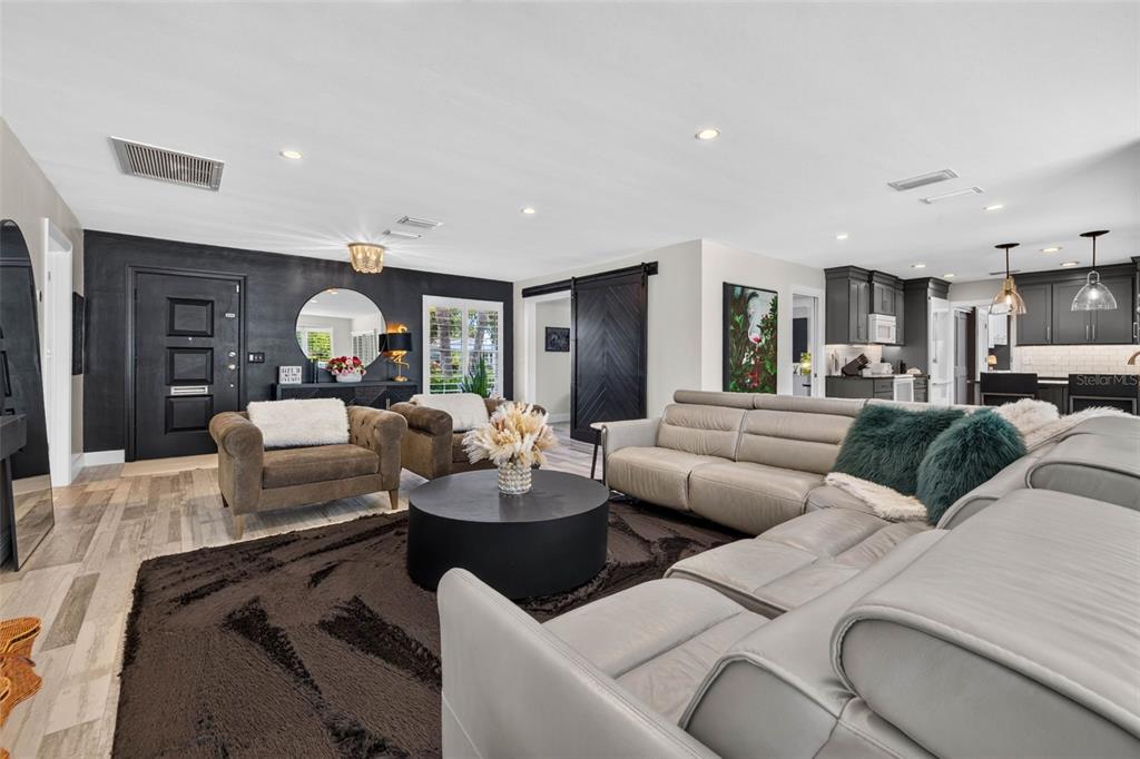 A living room features a grey sectional, two brown armchairs, and a black accent wall — 616 PINELAND AVENUE, BELLEAIR, FL