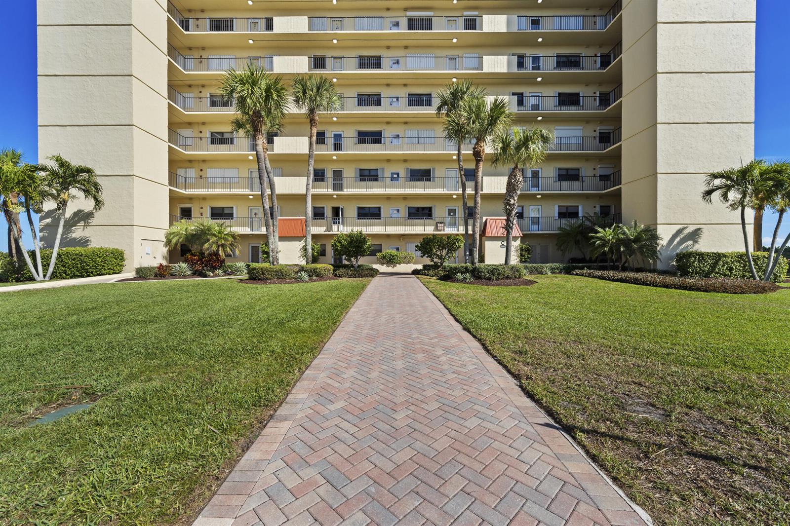 An aerial view of a multi-story beachfront apartment building with palm trees and landscaping — 7420 S Ocean Drive # 113, Jensen Beach FL 34957, JENSEN BEACH, FL