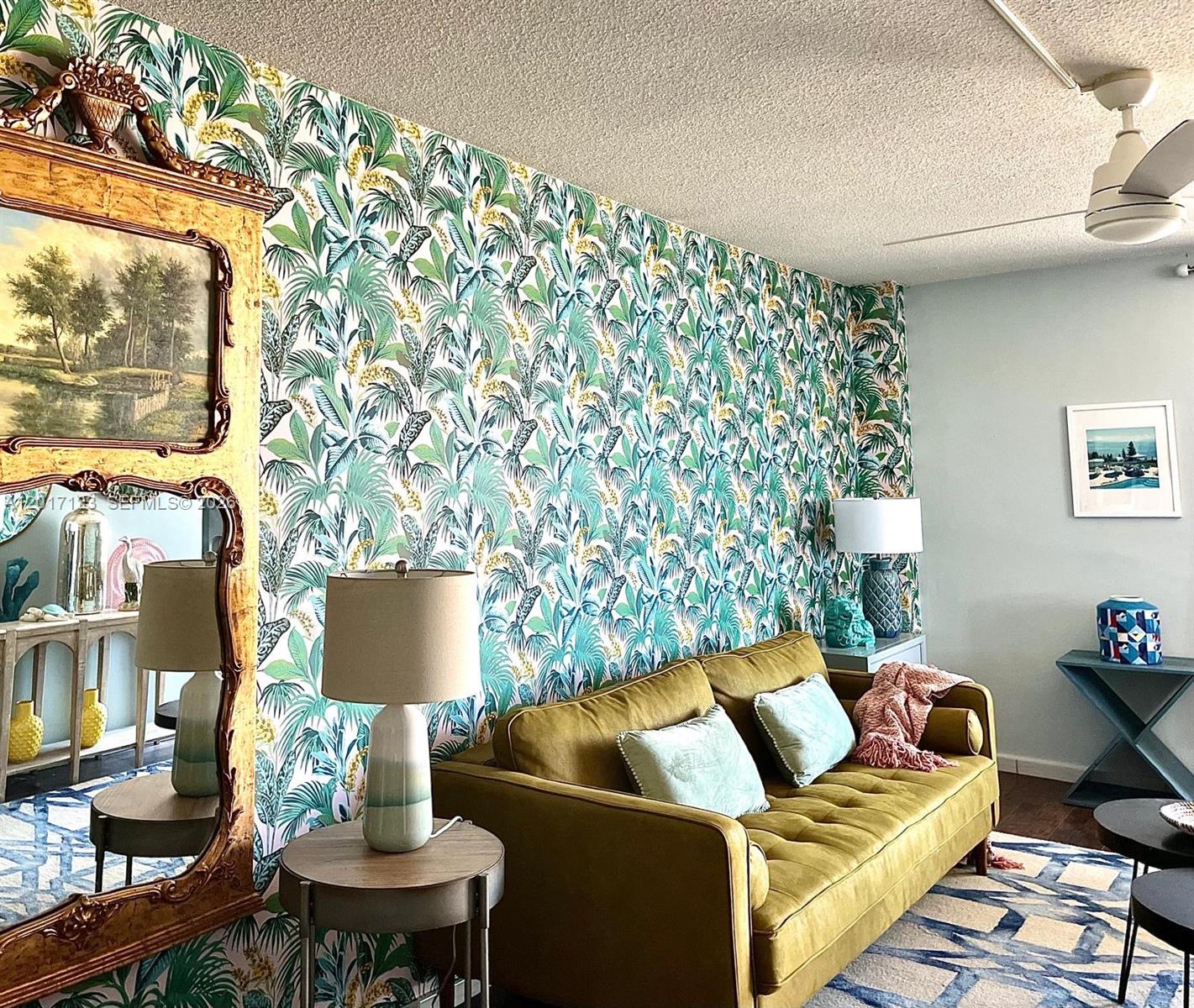 A living room features a palm-print accent wall, a mustard sofa, and a large ornate mirror — MIAMI BEACH, FL