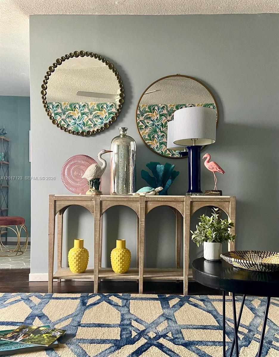 A console table with decorative coastal accents sits against a wall with two round mirrors — MIAMI BEACH, FL