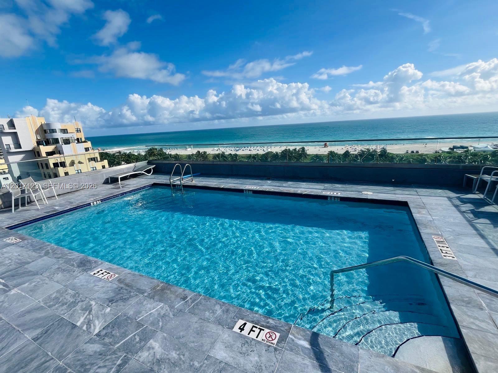 A rooftop swimming pool overlooks the ocean and a sandy beach — MIAMI BEACH, FL