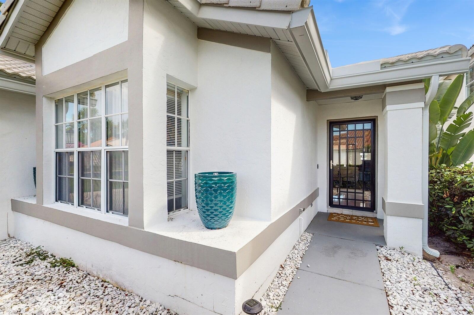 The exterior of a white house features a front door, a window, and a planter — 2690 Linkside Drive, Wellington FL 33414, WELLINGTON, FL