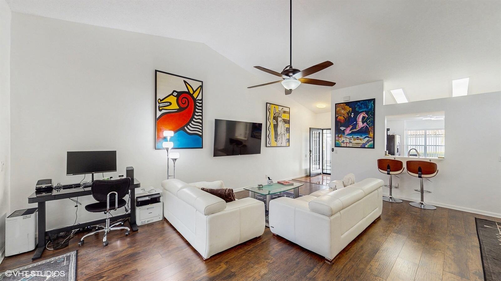 A living room features white leather sofas, a wall-mounted television, and wood-look flooring — 2690 Linkside Drive, Wellington FL 33414, WELLINGTON, FL