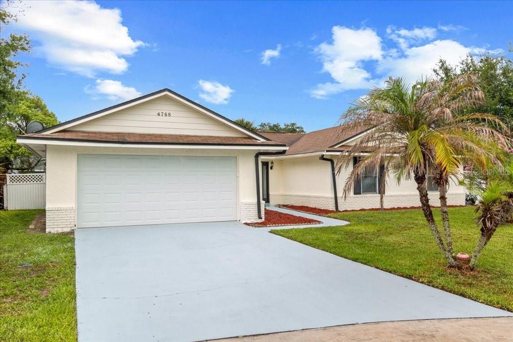 A single-story house with a white exterior, a two-car garage, and a palm tree — 4768 CROSSBOW COURT, ORLANDO, FL