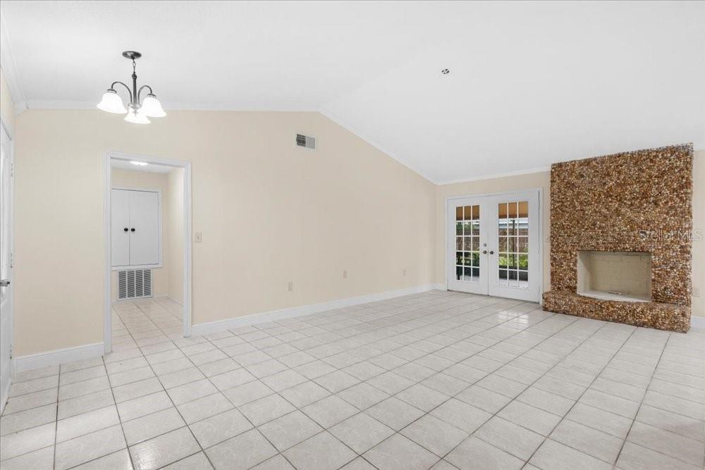A living room with white tile floors, a vaulted ceiling, and a stone fireplace — 4768 CROSSBOW COURT, ORLANDO, FL