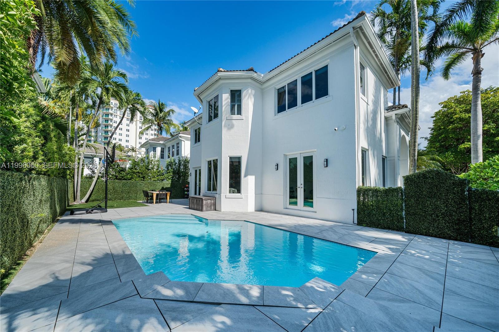 A modern kitchen with a large marble island, white cabinetry, and wood-look tile flooring — 3703 NE 199th St, Aventura FL 33180, AVENTURA, FL