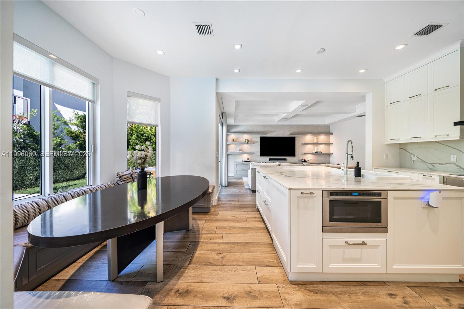 A modern kitchen features a white marble island, farmhouse sink, and an adjacent dining nook — 3703 NE 199th St, Aventura FL 33180, AVENTURA, FL