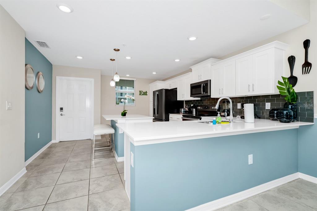 A kitchen features white cabinets, a teal accent wall, and a white breakfast bar — 3171 PARADOX CIRCLE UNIT 104, KISSIMMEE, FL