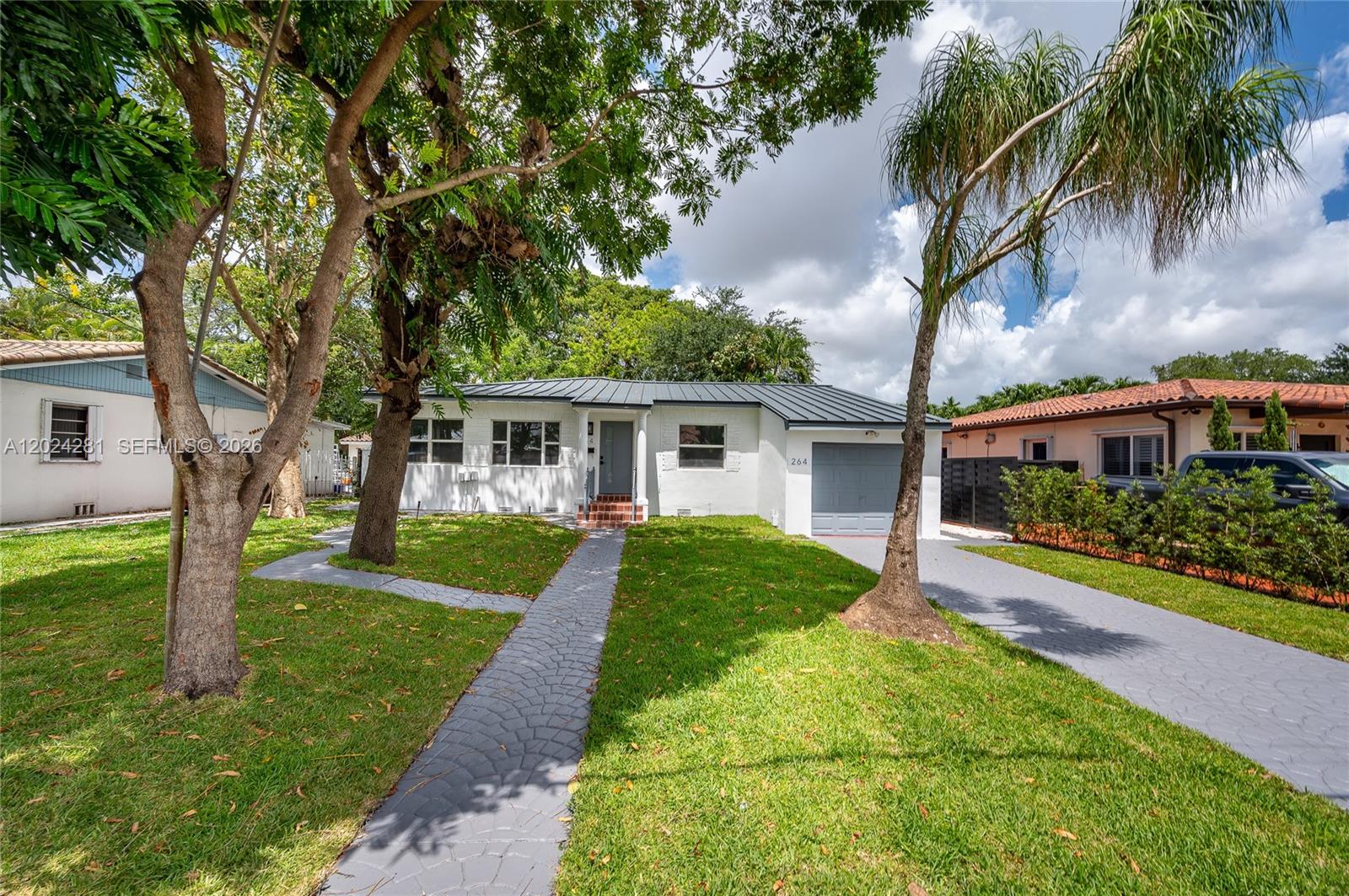 A single-story white house with a metal roof, a gray driveway, and a paved walkway — 264 Navajo St, Miami Springs FL 33166, MIAMI SPRINGS, FL