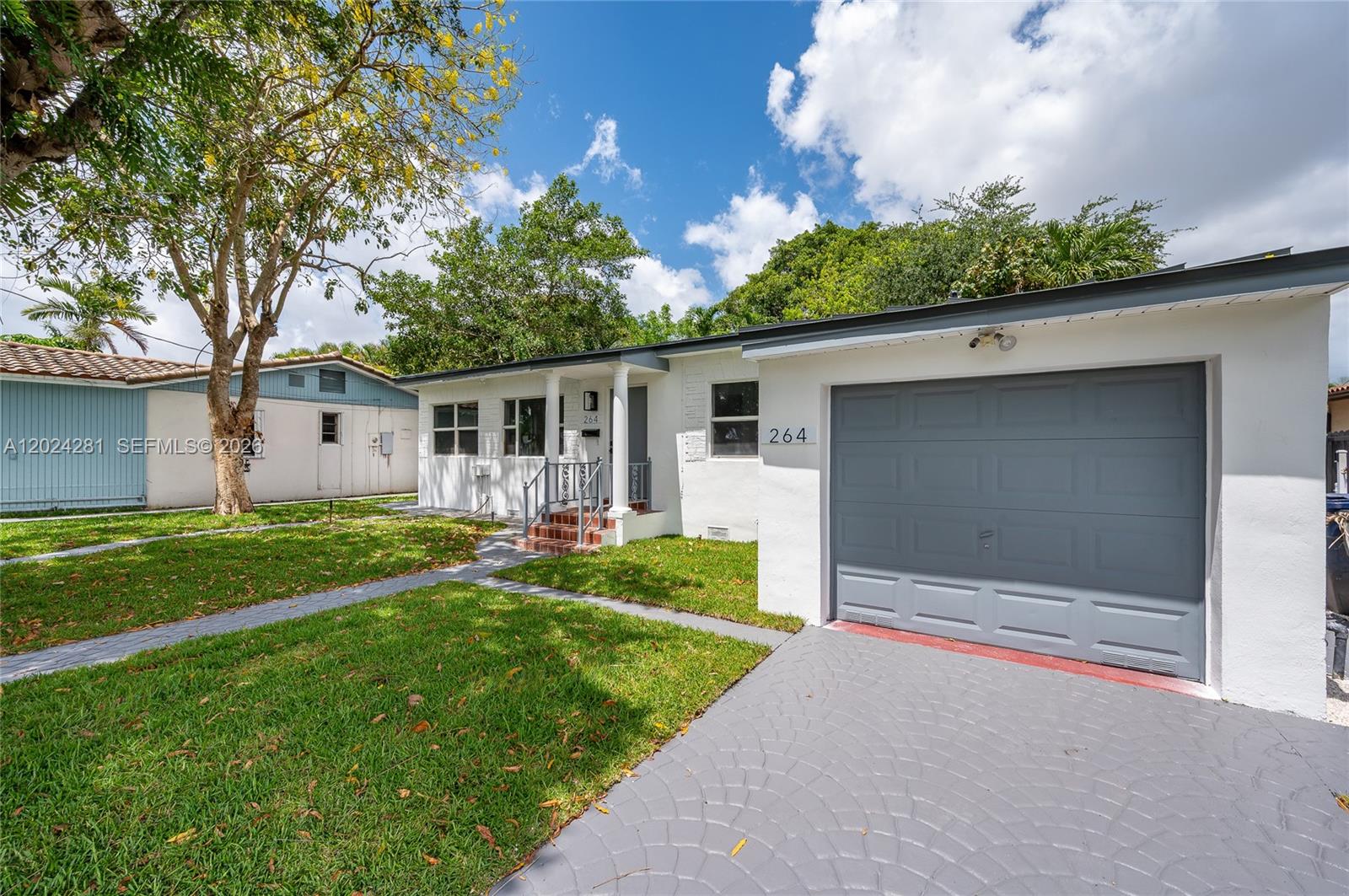 A white single-story house features a gray garage door and a front walkway — 264 Navajo St, Miami Springs FL 33166, MIAMI SPRINGS, FL