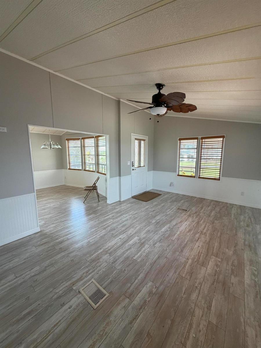A living room with wood-look flooring, white wainscoting, a ceiling fan, and an adjacent dining area — 5367 SE 66th Avenue, Okeechobee FL 34974, OKEECHOBEE, FL