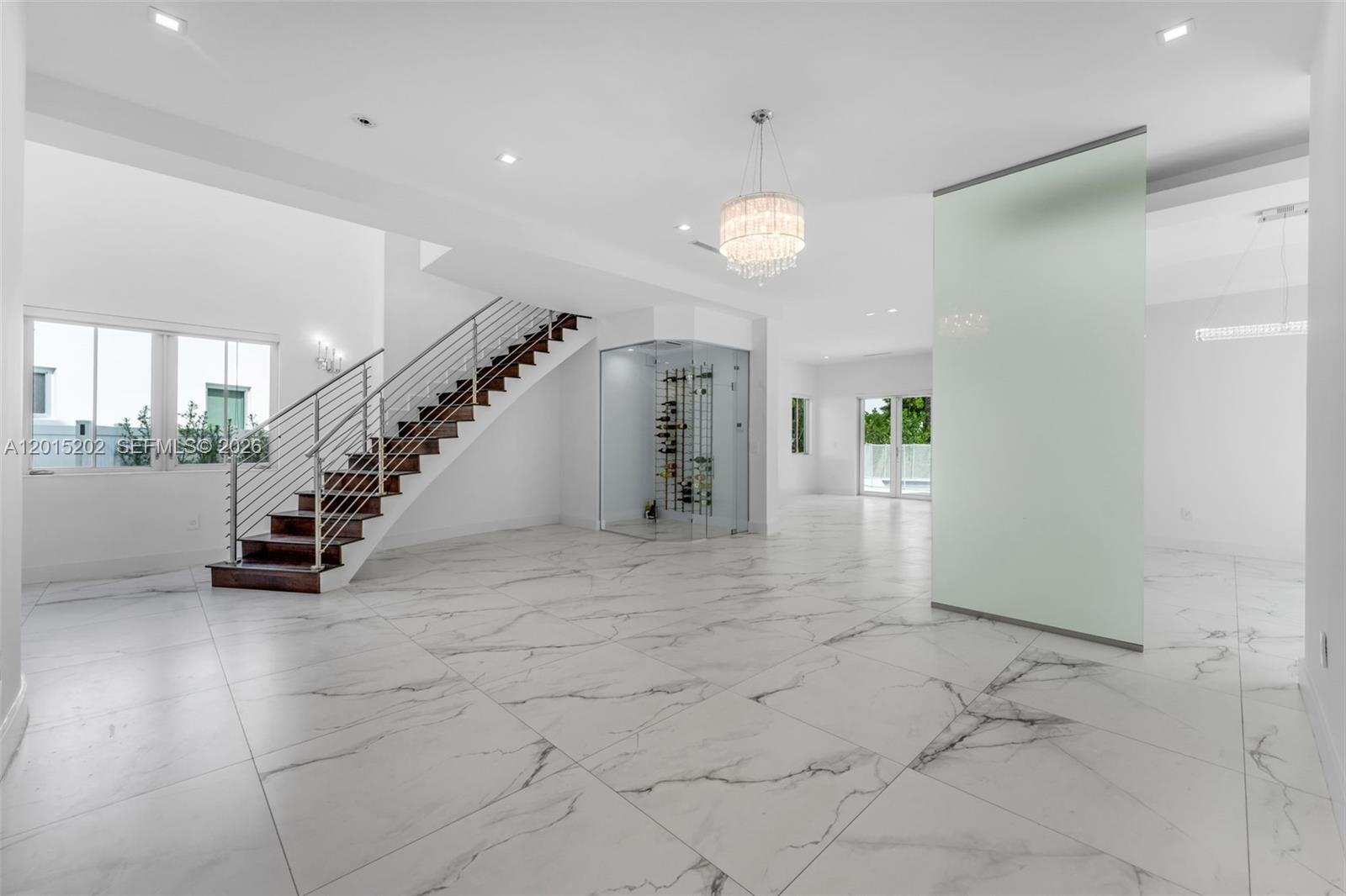 A spacious, modern room features white marble floors, a glass wine cellar, and a staircase — 8221 NW 34th Dr, Doral FL 33122, DORAL, FL