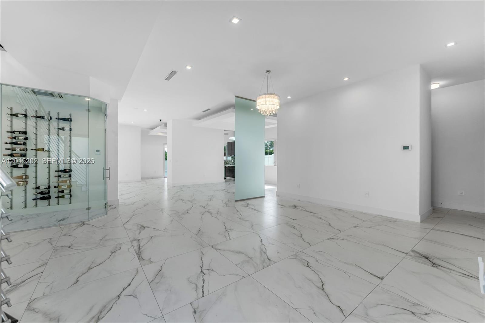 A bright, open-concept room features white marble flooring, a glass-enclosed wine cellar, and a chandelier — 8221 NW 34th Dr, Doral FL 33122, DORAL, FL