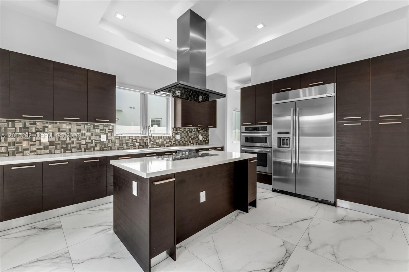 A modern kitchen features dark wood cabinetry, a central island, stainless steel appliances, and marble-patterned flooring — 8221 NW 34th Dr, Doral FL 33122, DORAL, FL