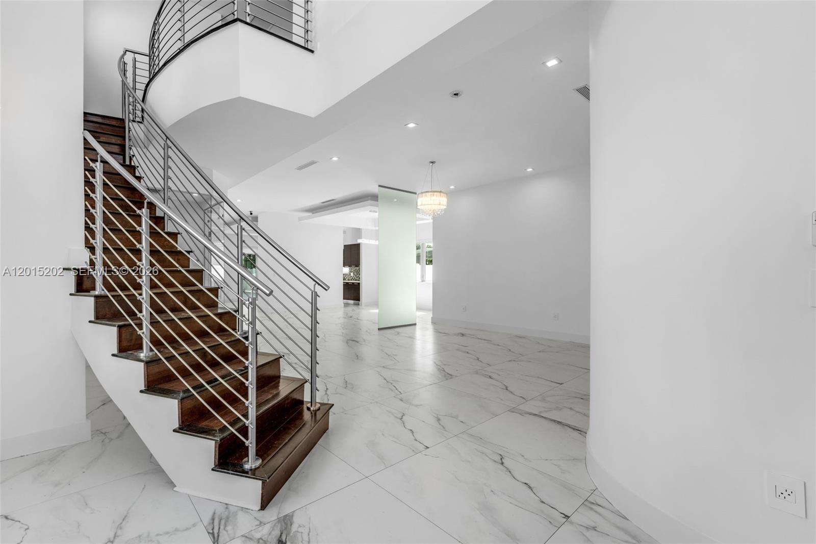 A modern interior features a wooden staircase with metal railings and white marble flooring — 8221 NW 34th Dr, Doral FL 33122, DORAL, FL