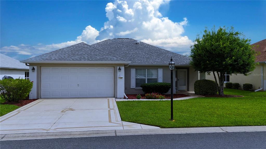A single-story suburban house with a two-car garage, gray roof, and a manicured lawn — 11981 SE 91ST CIRCLE, SUMMERFIELD, FL
