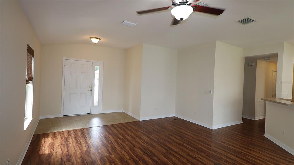 An entryway with tile flooring leads into a living area featuring wood-look laminate flooring — 11981 SE 91ST CIRCLE, SUMMERFIELD, FL
