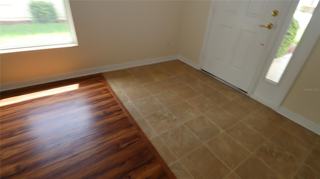 An entryway features a white front door, tan tile flooring, and adjacent wood-look flooring — 11981 SE 91ST CIRCLE, SUMMERFIELD, FL