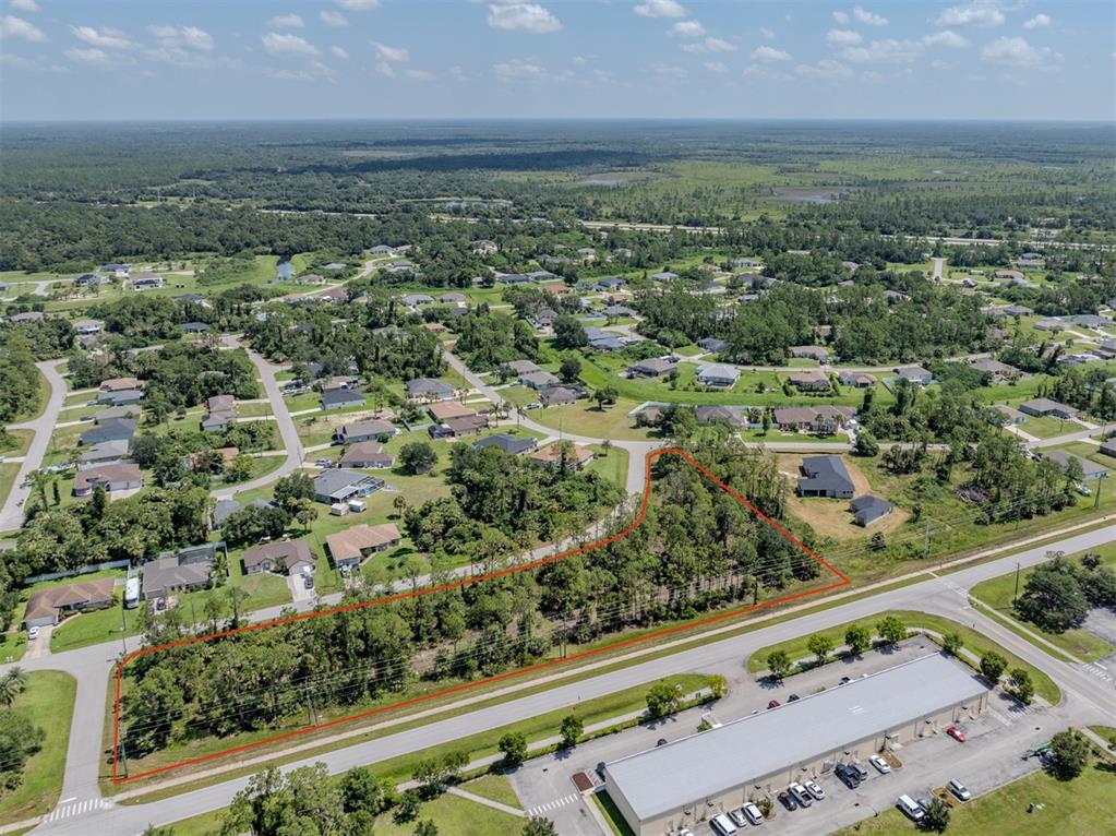 An aerial view shows a wooded, rectangular plot of land outlined in red near a road — MAGENTA AVENUE, NORTH PORT, FL