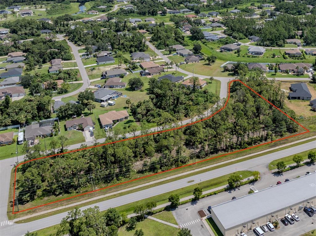 An aerial view shows a rectangular, tree-covered vacant lot outlined in red next to a road — MAGENTA AVENUE, NORTH PORT, FL