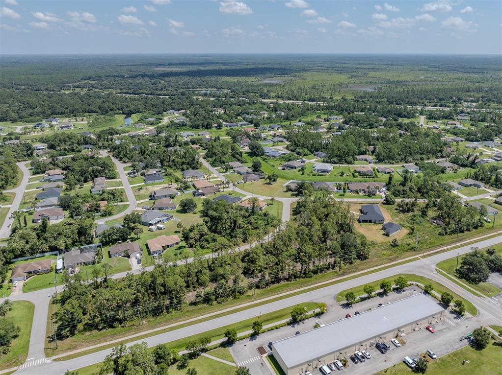 An aerial view shows a residential neighborhood adjacent to a commercial building and highway — MAGENTA AVENUE, NORTH PORT, FL