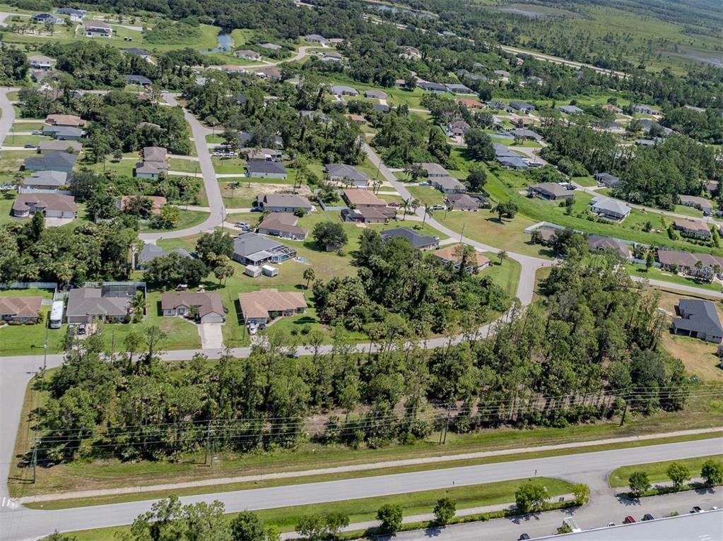 An aerial view shows a suburban neighborhood with houses, winding roads, and surrounding wooded areas — MAGENTA AVENUE, NORTH PORT, FL