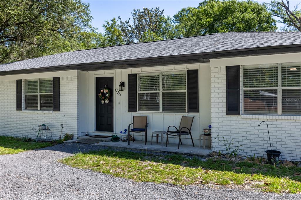 A single-story house with white brick siding, black shutters, and a gravel driveway — 926 WOODLAWN STREET, STARKE, FL