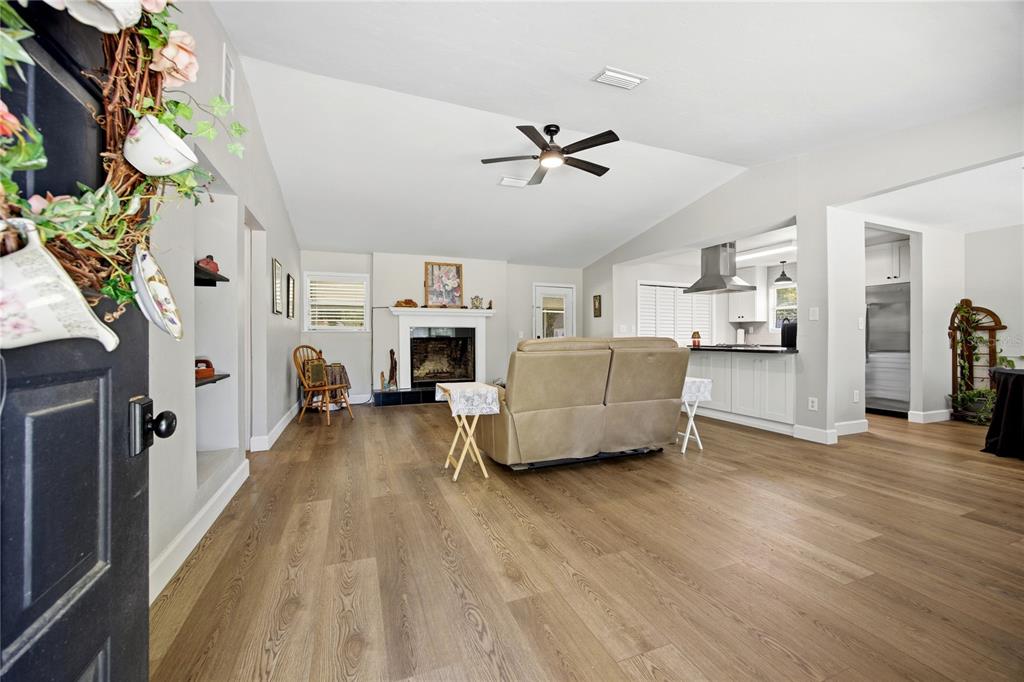 A living room with wood-look flooring, a fireplace, and an open kitchen in the background — 926 WOODLAWN STREET, STARKE, FL