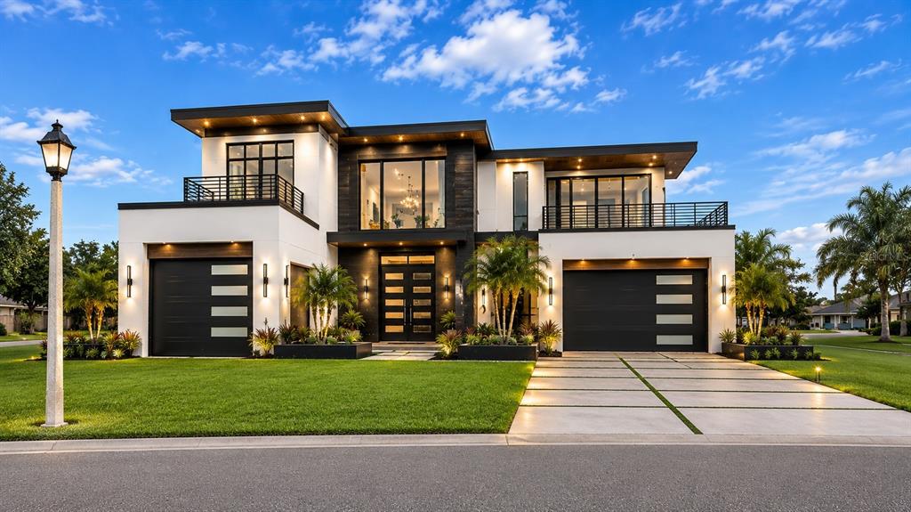 A modern two-story house with a flat roof, dark garage doors, and a concrete driveway — 5709 SUN VALLEY DRIVE, SEBRING, FL